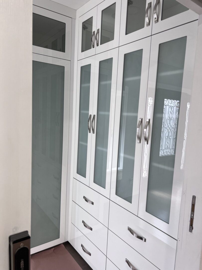 White built-in wardrobe with glass doors.
