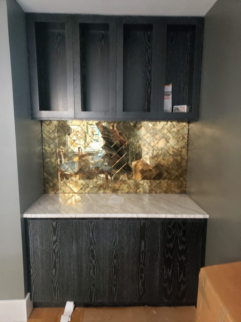 Black cabinets with gold mirrored backsplash.