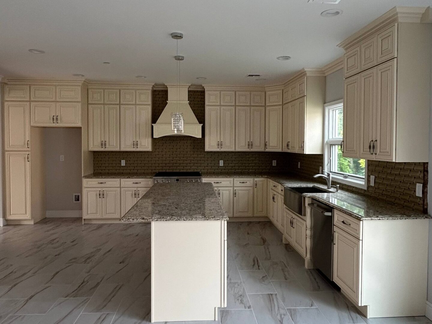 Modern kitchen with marble countertops and light wood cabinetry.