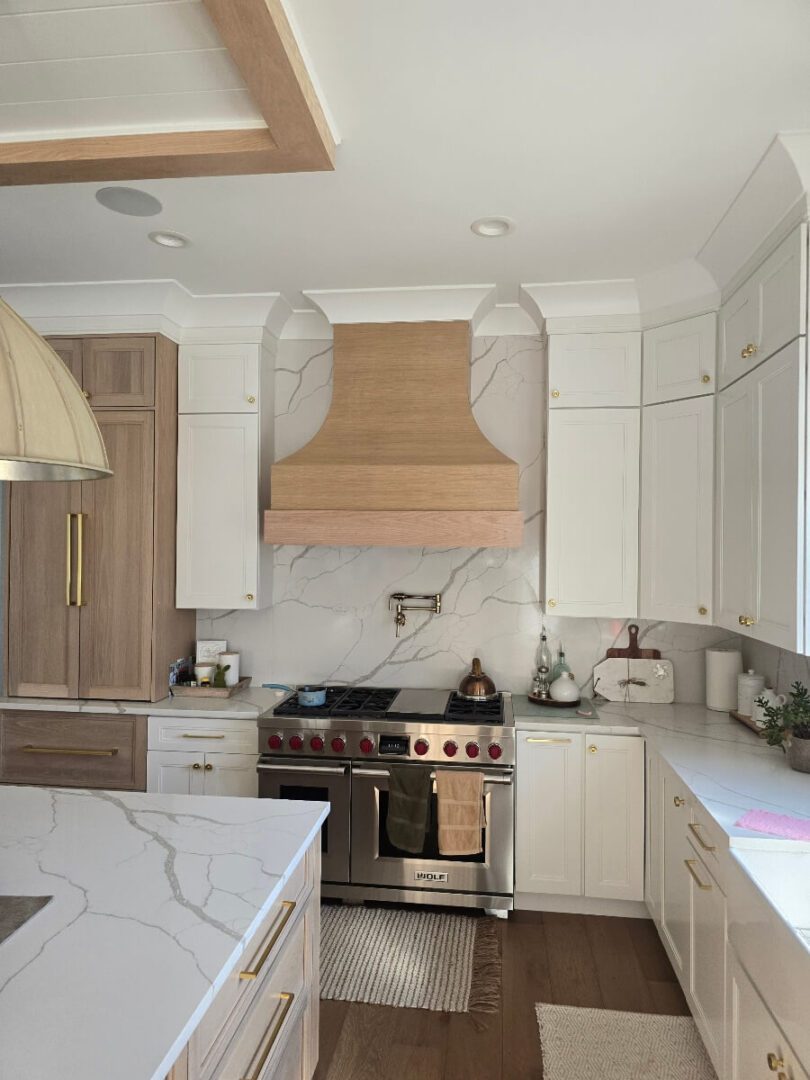 Modern kitchen with white cabinets and marble countertops.