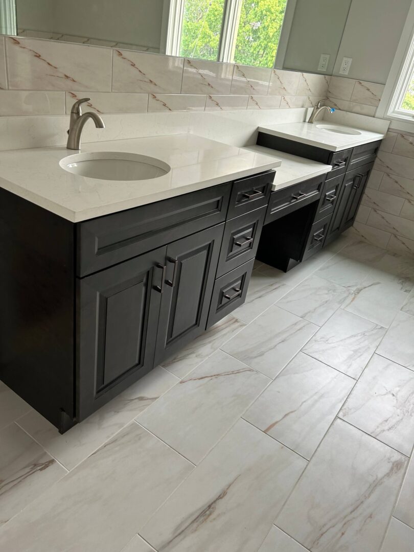Modern bathroom vanity with dark cabinets and light marble countertops.