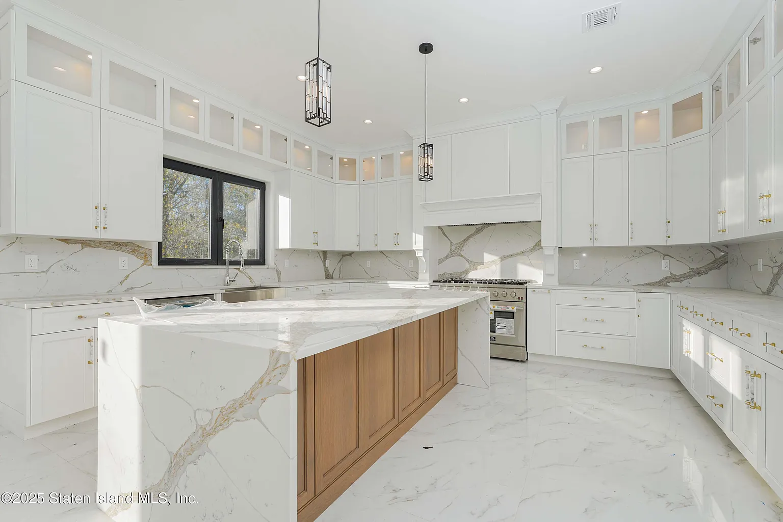 Modern kitchen with white cabinets and a marble island.