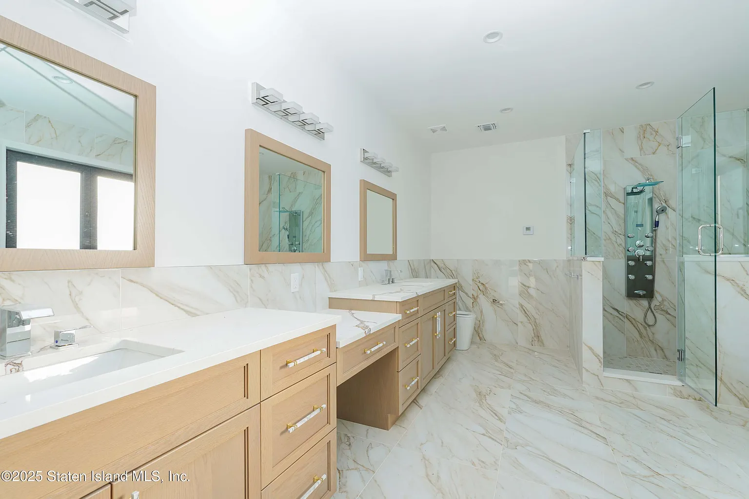 Modern bathroom with wooden cabinets and marble surfaces.