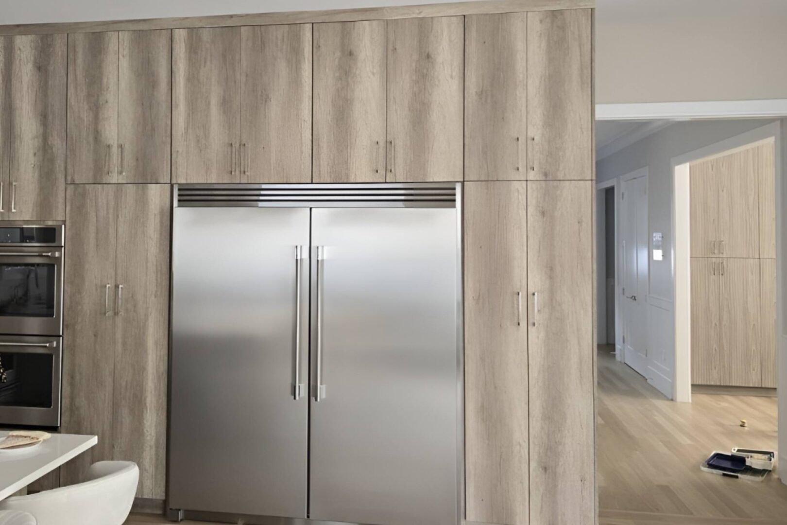 Modern kitchen with built-in stainless steel refrigerator and wooden cabinets.