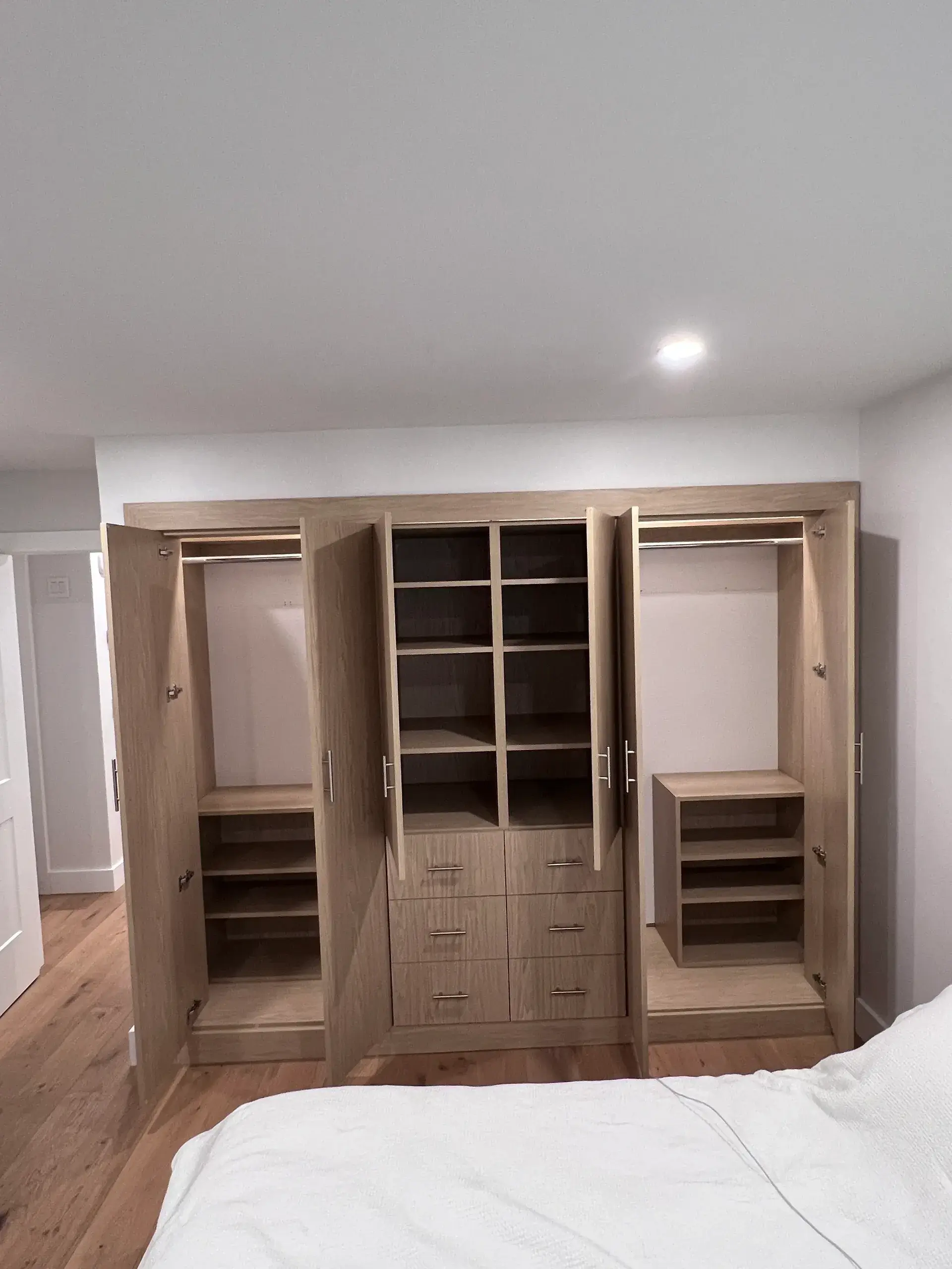 Open wooden wardrobe with shelves and drawers.