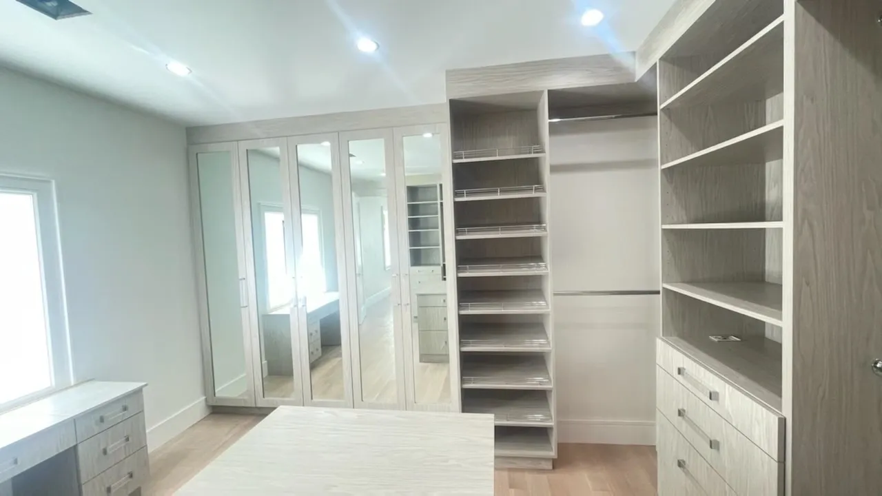 Spacious walk-in closet with mirrored doors.