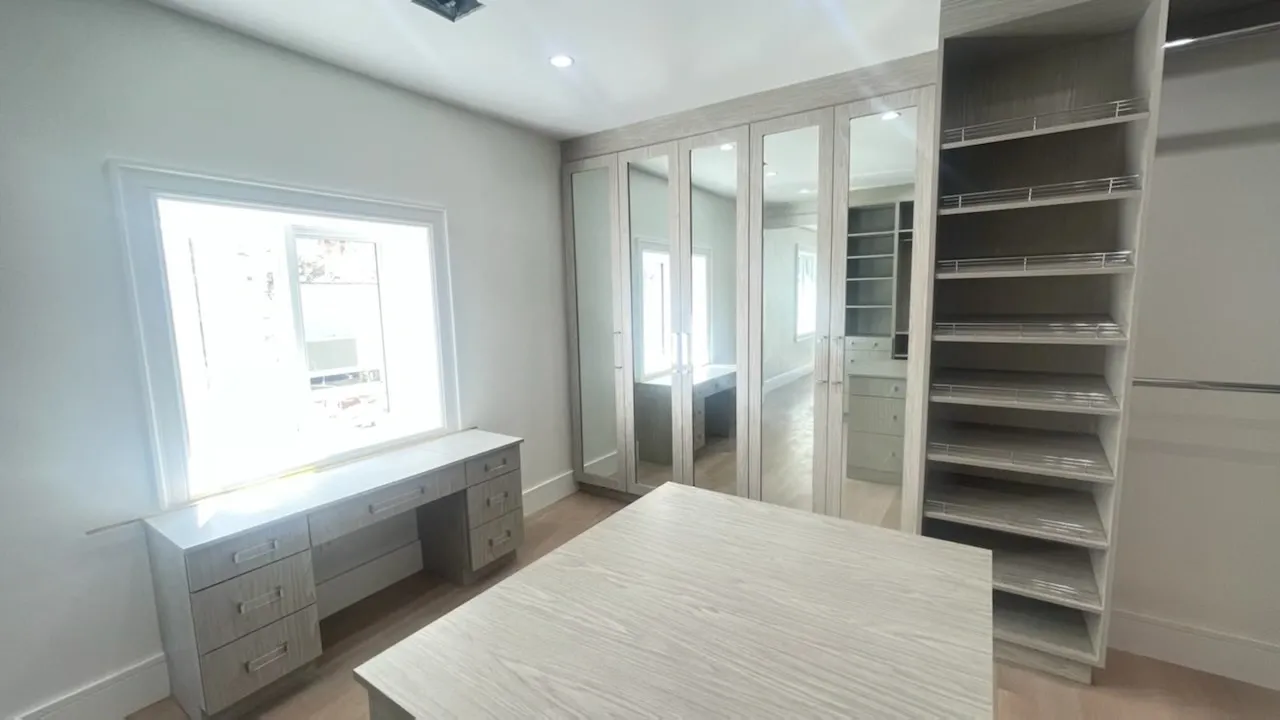 Modern walk-in closet with mirrored doors.