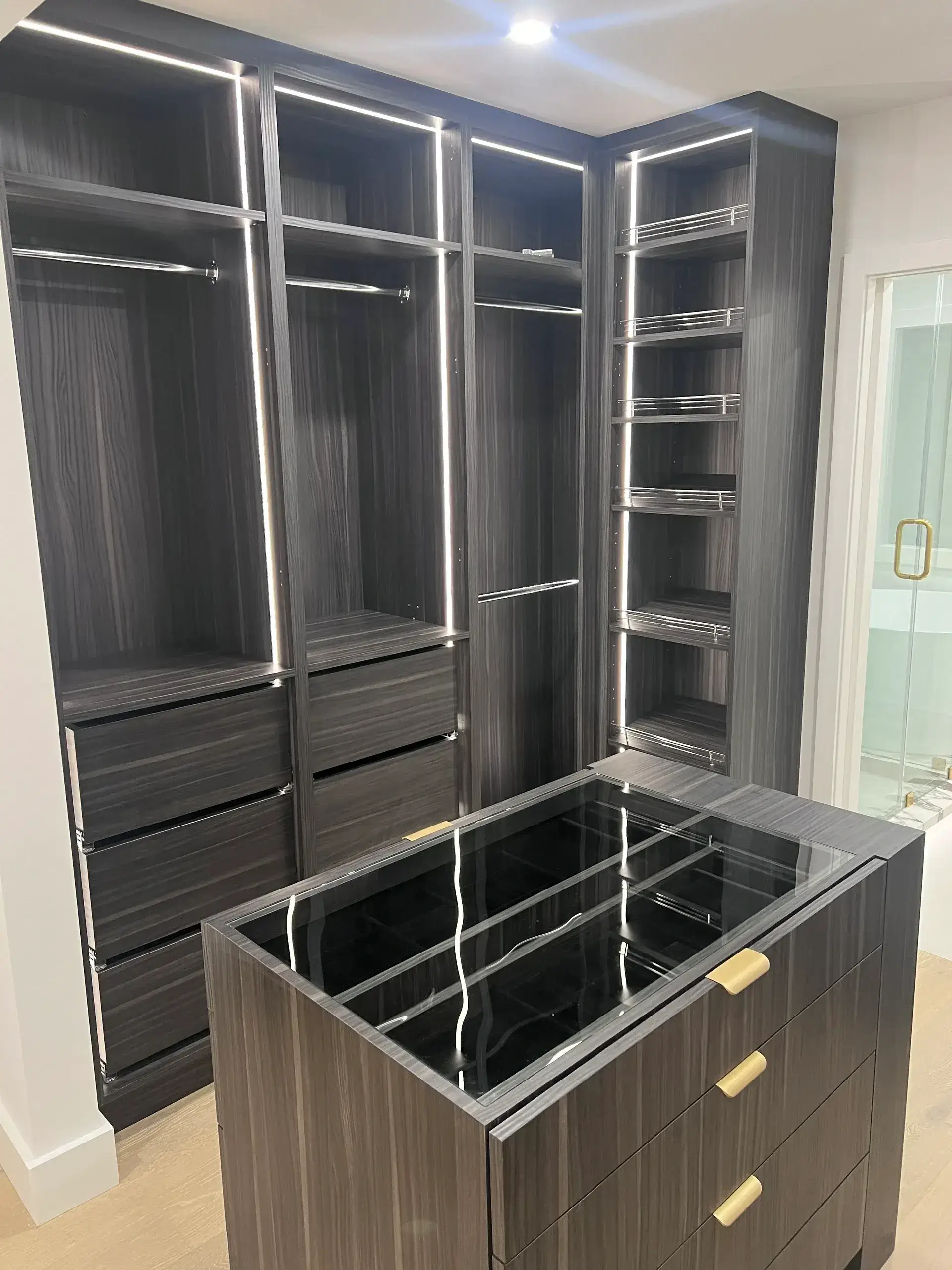 Modern walk-in closet with dark wood finish.