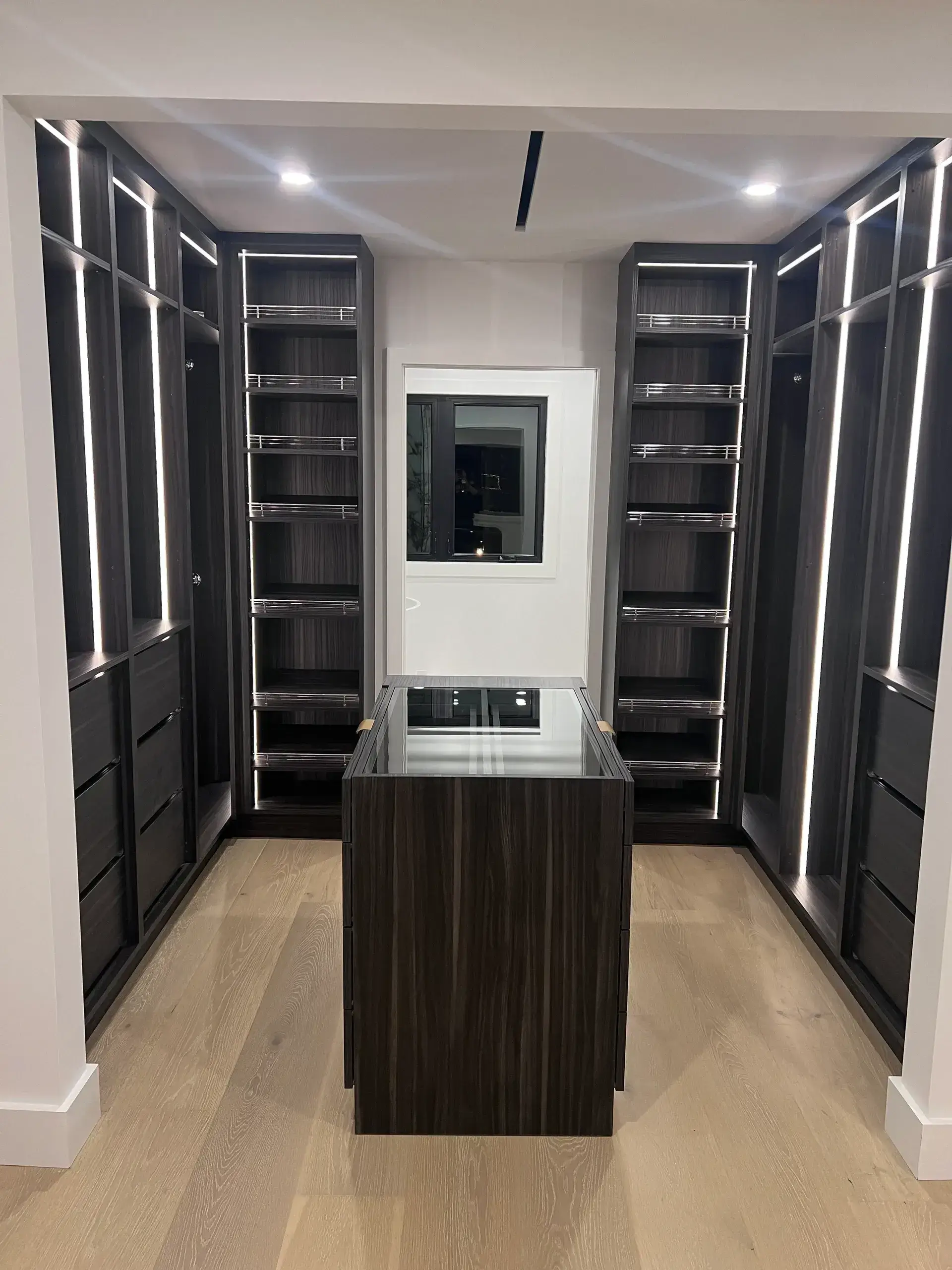 Modern walk-in closet with dark wood shelves.