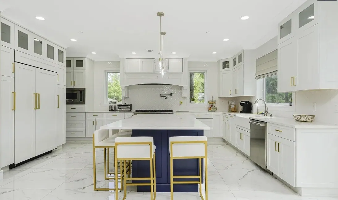 Bright white kitchen with navy island, gold stools